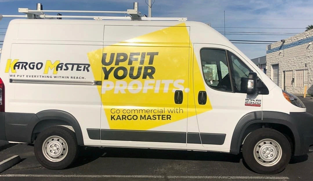 White van with yellow and black Kargo Master advertisement on a parking lot.
